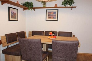 Ein Essbereich mit einem Holztisch und sechs gepolsterten Stühlen. Über dem Tisch befinden sich zwei gerahmte Bilder an der Wand.