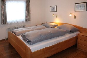 Ein Doppelbett mit Holzgestell, ein Nachttisch und eine Heizung.