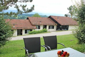 Ein Gebäude mit rotem Ziegeldach, einem gepflasterten Einfahrtsweg und einem Tisch mit Stühlen sowie einer Obstschale.