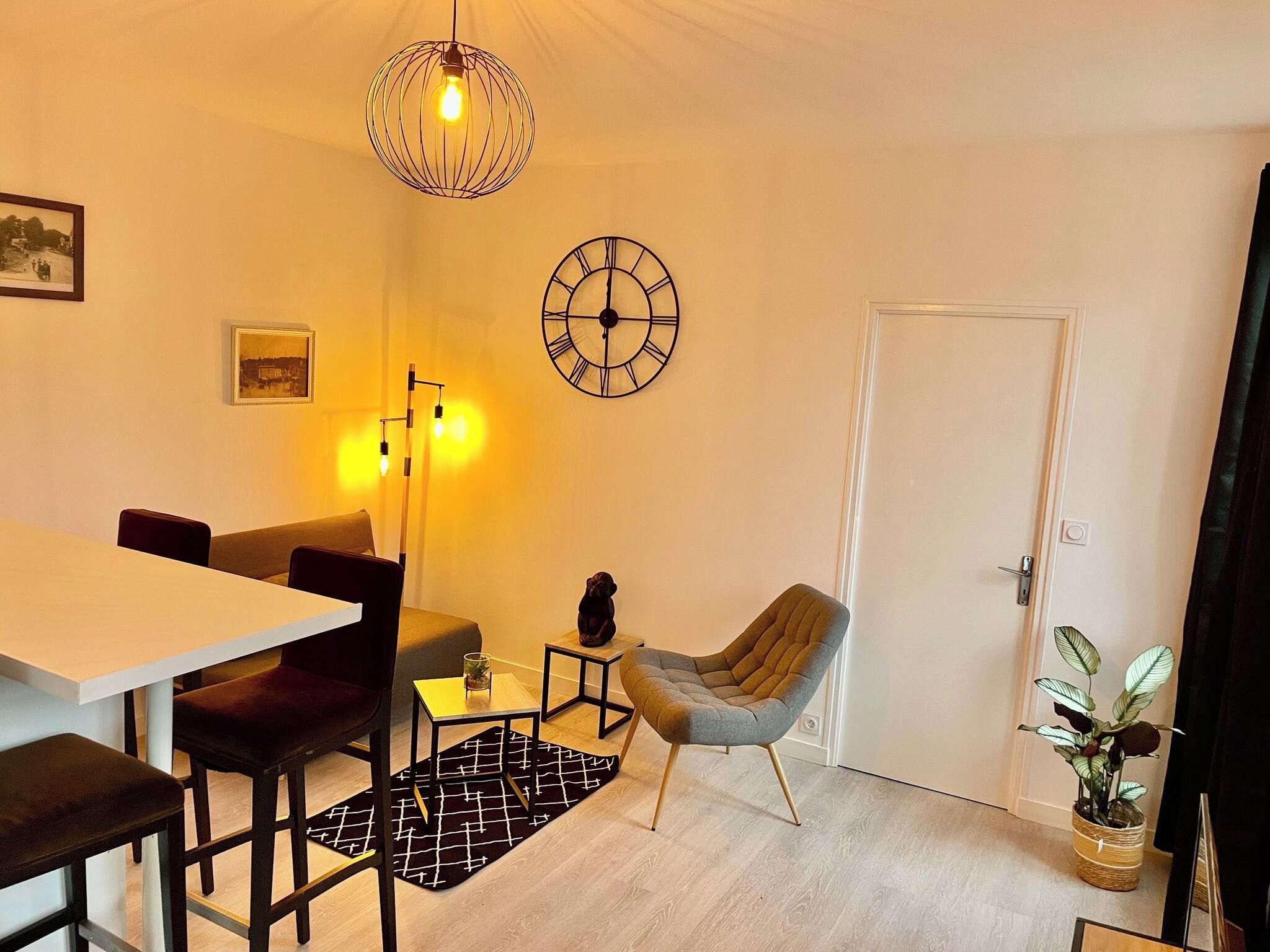 A dining area with a table, chairs, a clock, and a hanging light fixture.