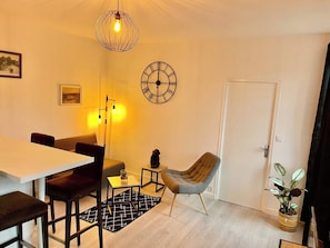 Un comedor con una mesa, sillas, un reloj y una lámpara colgante.
