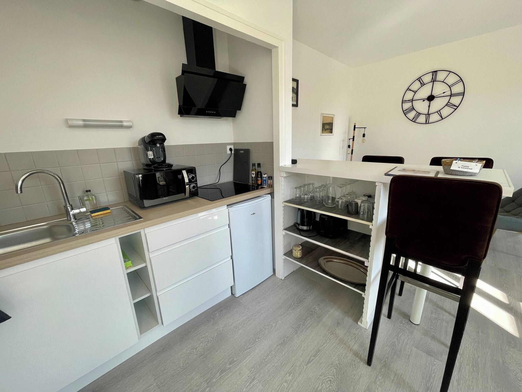 Cocina compacta con microondas, cafetera y refrigerador pequeño.