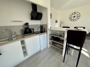 Cocina compacta con microondas, cafetera y refrigerador pequeño.