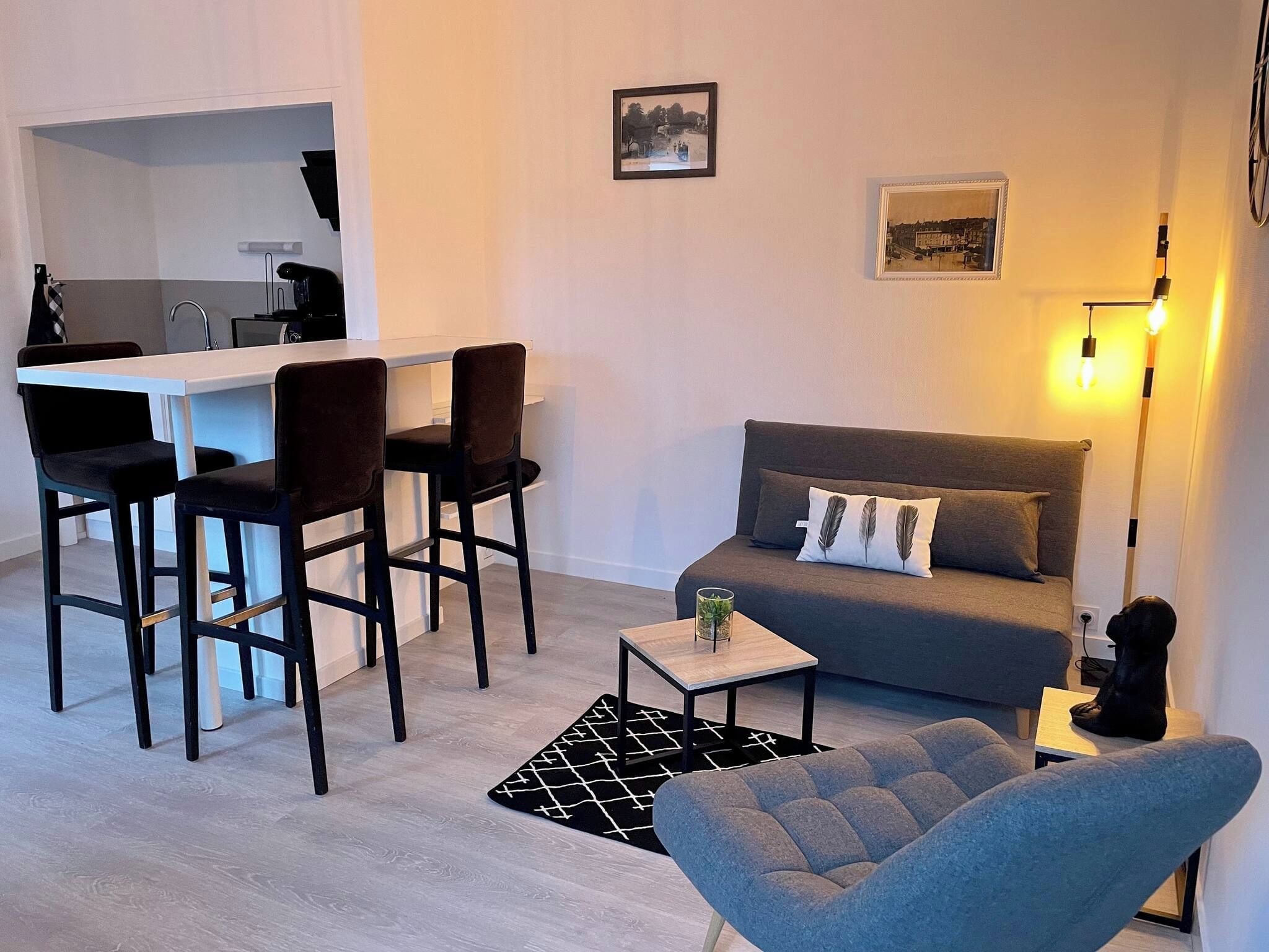 Een knus woongedeelte met een kitchenette, een bank, een salontafel en een eethoek met stoelen.
