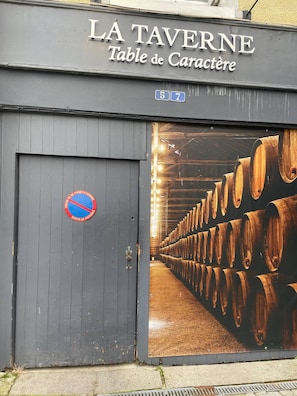 Un edifici amb un cartell que diu 'LA TAVERNE Table de Caractère' i un senyal blau amb un cercle vermell i una línia diagonal que indica prohibit aparcar.