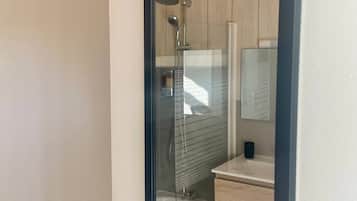 Une salle de bain équipée de toilettes, d’une douche et d’un lavabo avec un miroir.