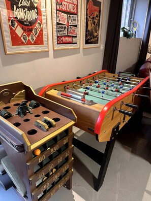 A foosball table with a wooden base and red accents, surrounded by framed posters on the wall. - House on the Riverbank in Downtown with a Pool (Vitré)