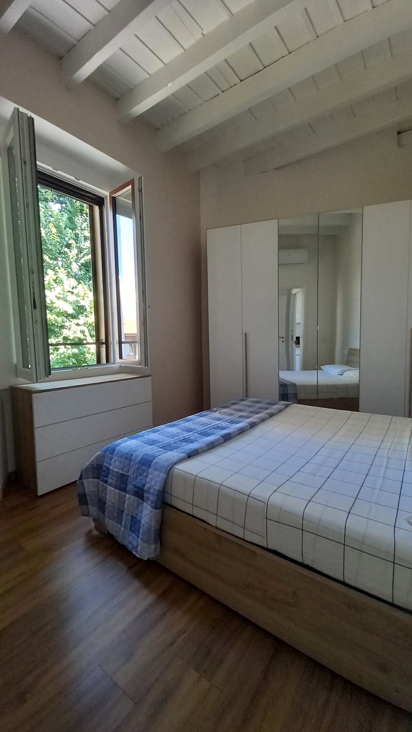 A bedroom with a bed, a window, and a wardrobe.