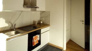 Een moderne keuken met witte kasten, een zwart aanrecht en een houten vloer.