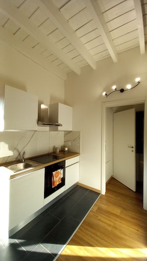 Une cuisine moderne avec des meubles blancs, un plan de travail noir et un plancher en bois.