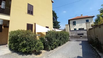 Una stretta via con un edificio giallo a sinistra e uno bianco a destra. Al centro, un cancello.