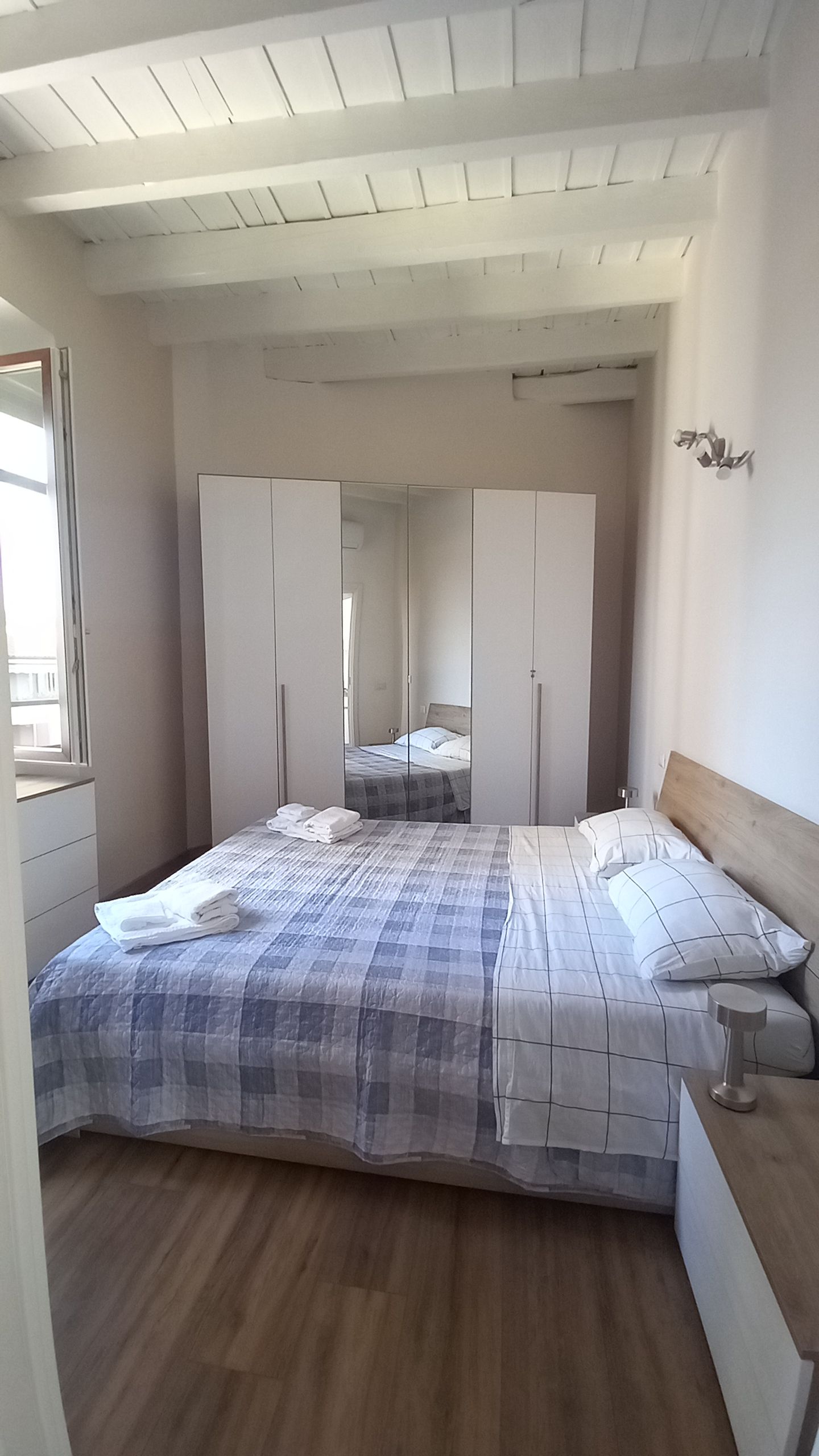 Una camera da letto con un letto, un armadio, uno specchio e un comodino.