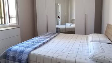Una camera da letto con un letto, un armadio, uno specchio e una finestra.