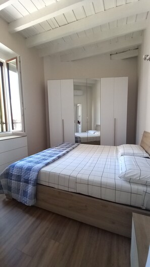 Een slaapkamer met een bed, een kledingkast, een spiegel en een raam.