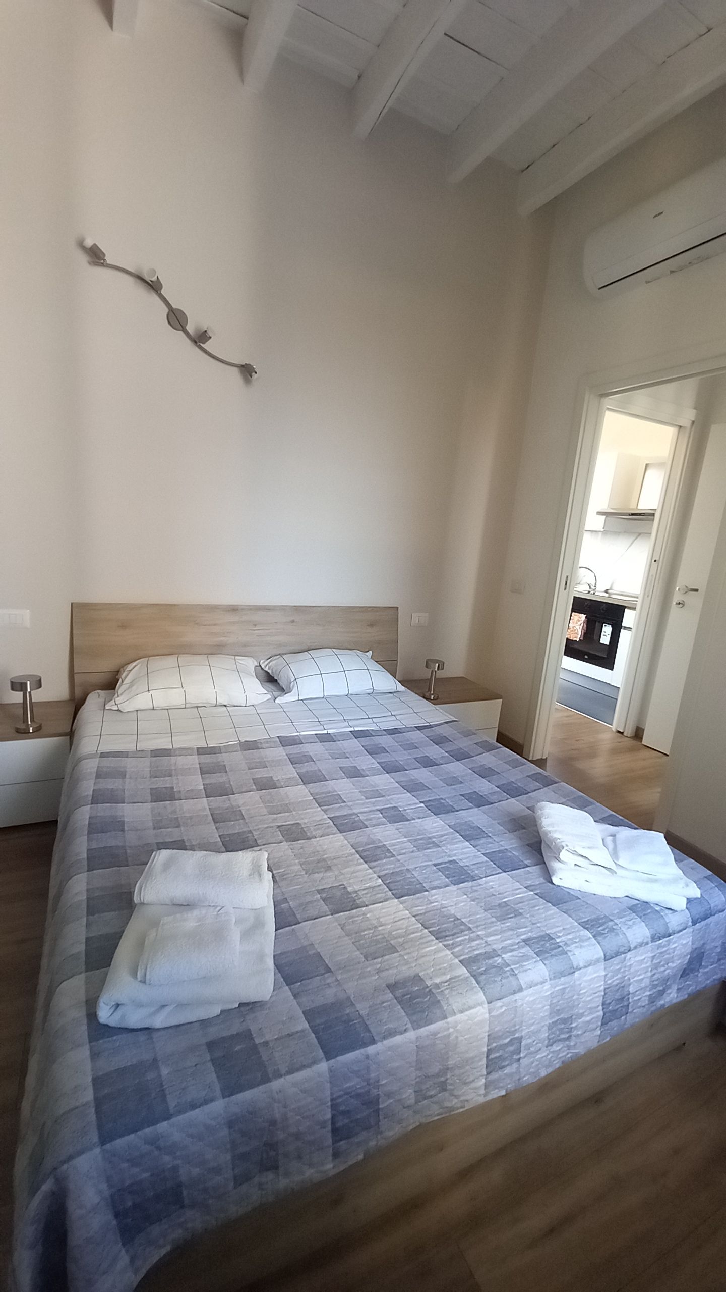 Une chambre à coucher avec un grand lit, une tête de lit en bois, une décoration murale en forme de branche et une porte donnant accès à une salle de bain.