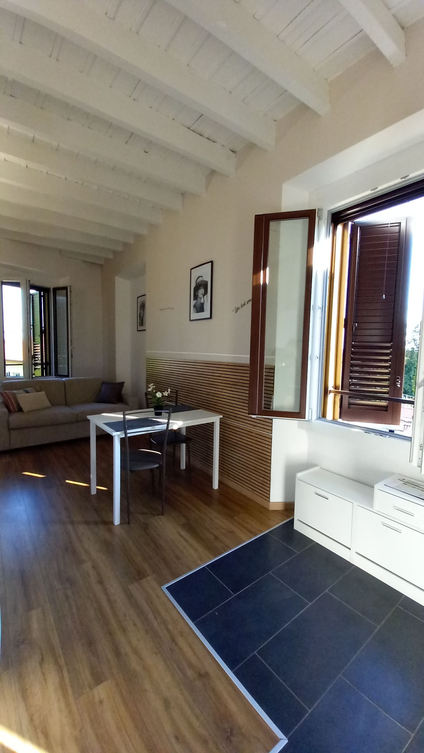 Een modern interieur met een eethoek, een bank en een groot raam met luiken.