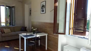 Een modern interieur met een eethoek, een bank en een groot raam met luiken.