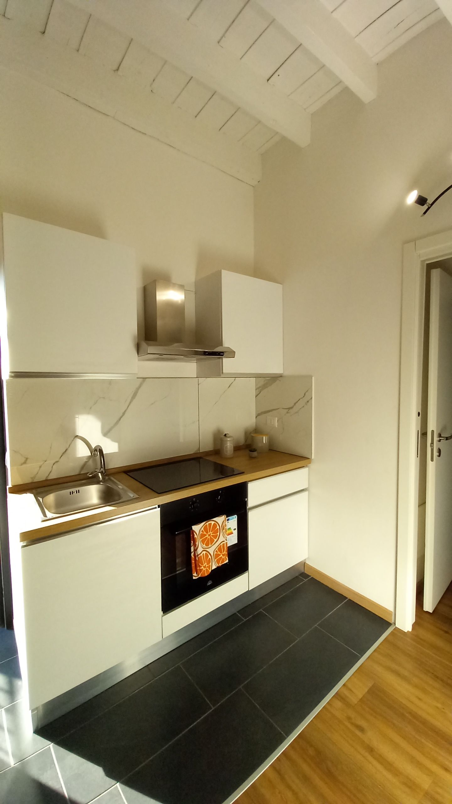 A modern kitchen with a built-in oven, stainless steel sink, and a wooden countertop.