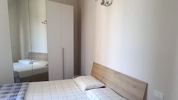 Een slaapkamer met een houten bed, een kledingkast en een spiegel.