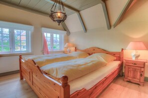 Une chambre à coucher avec un lit en bois, deux tables de chevet et un luminaire suspendu.