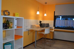 A compact kitchen with white shelves, a white countertop, two hanging pendant lights, and a window with a view of the outside. - Holiday home with 5 bedrooms (Schleiden-Gemünd)