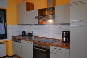 Une cuisine avec des armoires blanches, une hotte de cuisinière en acier inoxydable, un lave-vaisselle et une machine à café.