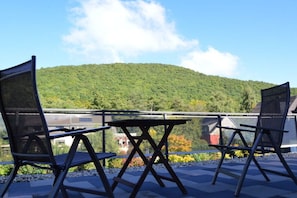 A balcony with two chairs and a table, overlooking a green hill. - Holiday home with 5 bedrooms (Schleiden-Gemünd)