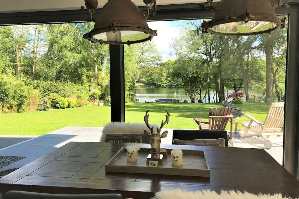 A dining area with a view of a pond and trees, a deer head centerpiece, and a sign with a name.
