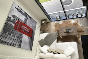 A modern interior with a white sofa, a red telephone booth artwork, and a glass ceiling. - Holiday home with 3 bedrooms (Ganderkesee)