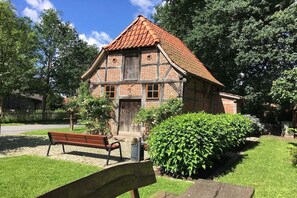 A traditional half-timbered house with a sloped roof, a wooden bench, and a well-maintained garden. - Holiday home with 3 bedrooms (Ganderkesee)