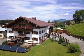 A two-story chalet with a balcony, a covered patio, and a view of the mountains. - Holiday apartment with 2 bedrooms (Sonthofen)