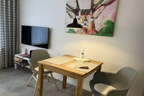 A room with a wooden table, two chairs, a television, and a painting on the wall. - Alpenflair holiday apartment 235 (Oberstdorf)