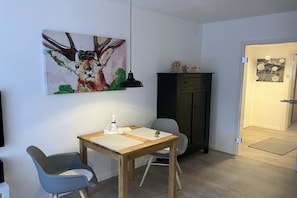A dining area with a wooden table, two chairs, a pendant light, and a cabinet. - Alpenflair holiday apartment 235 (Oberstdorf)