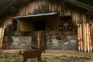A rustic wooden building with a stone wall and a metal door. - Alpenflair holiday apartment 235 (Oberstdorf)