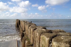 A coastal scene with a series of concrete sea defenses extending into the water. - Holiday home in Norddorf with swimming pool (Norddorf)