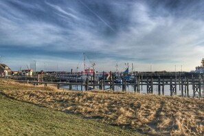 A marina with boats docked, a pier extending into the water, and a grassy area in the foreground. - Holiday home in Norddorf with swimming pool (Norddorf)