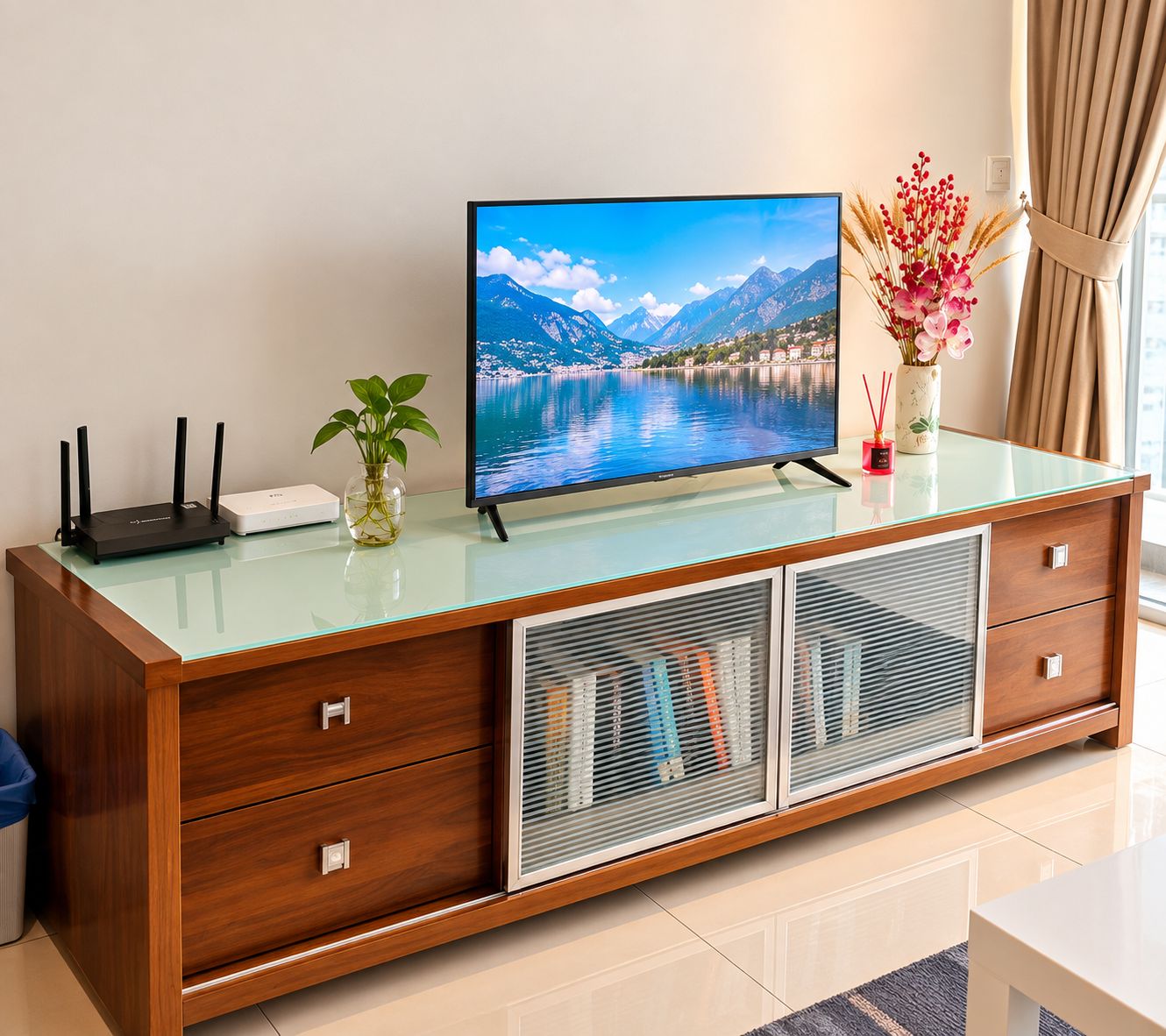Un meuble TV en bois avec un plateau en verre, un téléviseur à écran plat et un vase rempli de fleurs.