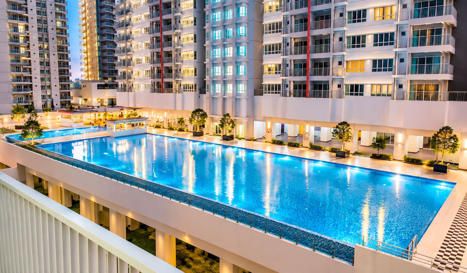 A swimming pool with a surrounding walkway, adjacent to high-rise residential buildings.