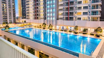 A swimming pool with a surrounding walkway, adjacent to high-rise residential buildings.