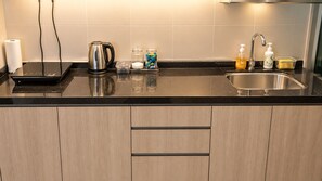 Een moderne keuken met een zwart aanrecht, een roestvrijstalen waterkoker en een spoelbak met zeepdispenser.
