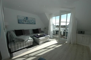 A living room with a sofa, a coffee table, and a painting on the wall. - Risgap holiday apartment 11c/5 (Wenningstedt)