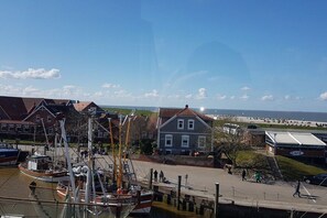A coastal marina with boats docked, a café, and a beach in the background. - Holiday apartment with 1 bedroom (Neuharlingersiel)