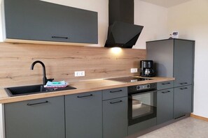 A modern kitchen with a built-in oven, a coffee maker, and a sink. - Holiday apartment with 1 bedroom (Neuharlingersiel)