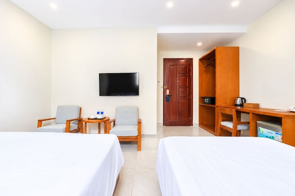A hotel room with two beds, a TV, a desk with a chair, and a wardrobe. - Nam Chau Stelar Hotel (Phu Quoc)