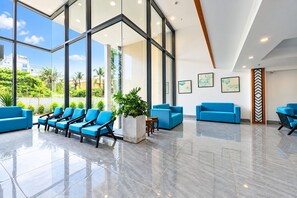 Eine moderne Lobby mit Glaswand, blauen Sitzgelegenheiten und Kunstwerken.