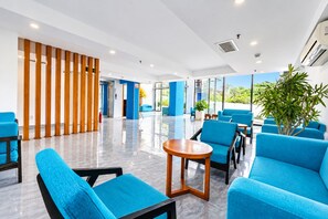 Eine moderne Lobby mit blauen Sitzgelegenheiten, einer Holzwand und Blick ins Freie.