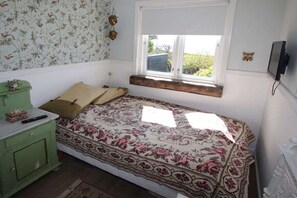A bedroom with a bed, a window, a green dresser, and a television. - Top Wadden Sea holiday home (Esbjerg)