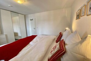 Ein Schlafzimmer mit einem Bett, einer roten Tagesdecke und einer weißen Tür.