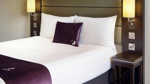 A hotel room with a large bed, two bedside lamps, and a headboard with built-in lighting. - Banbury (M40, J11) (Banbury)