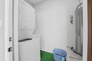 Une buanderie équipée d’un lave-linge, d’un sèche-linge et d’un chauffe-eau.